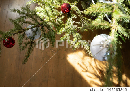 Christmas tree branches with red and white ornaments in sunlight Christmas tree branches with red and white ornaments in sunlight 142285846