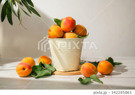 Fresh ripe apricot fruits in white bucket on sunlit rustic table, bright and airy food background with copy space Fresh ripe apricot fruits in white bucket on sunlit rustic table, bright and airy food background with copy space 142285863
