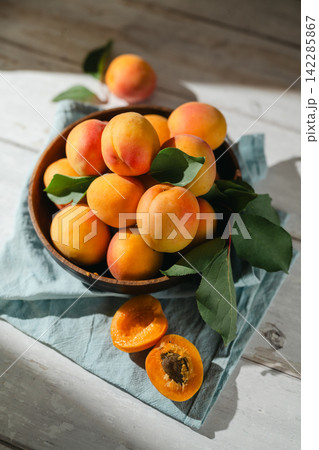 Close-up apricot fruits on a plate with leaves, healthy summer abstract food background Close-up apricot fruits on a plate with leaves, healthy summer abstract food background 142285867