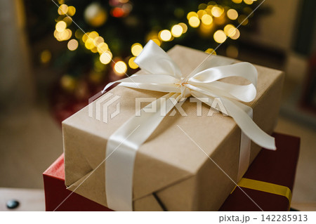 Holiday background, gift boxes next to Christmas tree. Abstract Christmas background, lifestyle. Copy space Holiday background, gift boxes next to Christmas tree. Abstract Christmas background, lifestyle. Copy space 142285913