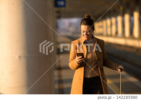 Relaxed Female Traveler Checking Phone at Train Platform Relaxed Female Traveler Checking Phone at Train Platform 142285980