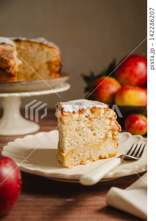 Slice of homemade apple cake with cinnamon, wooden background, lifestyle moody food photo 142286207