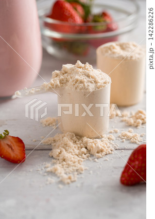 Scoop of protein powder and strawberry smoothie glass with fresh berries 142286226