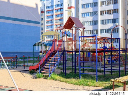 Playground for children located in urban apartment block yard. Concept of outdoor active play, kids recreation area Playground for children located in urban apartment block yard. Concept of outdoor active play, kids recreation area 142286345