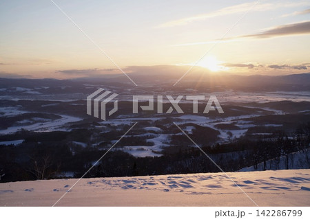 雪原に落ちる夕日と霞む平野 142286799