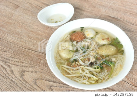 boiled rice vermicelli noodles fish and shrimp meatball couple dumping with bean sprout dressing chop pork in clear soup on bowl dipping spicy chili vinegar sauce 142287159