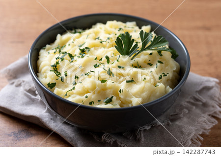 Creamy mashed potatoes with fresh parsley on wooden table Creamy mashed potatoes with fresh parsley on wooden table 142287743