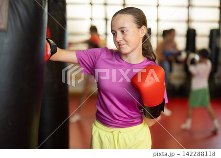Teenage girl in boxing gloves in training Teenage girl in boxing gloves in training 142288118