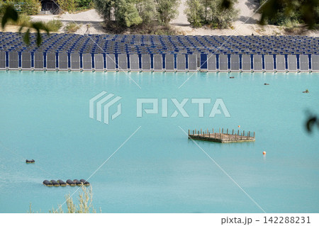 Vertical floating solar panels on the Gilching quarry lake in Bavaria, Germany, beside a gravel and crushing plant, renewable energy infrastructure, industrial landscape and innovative clean 142288231