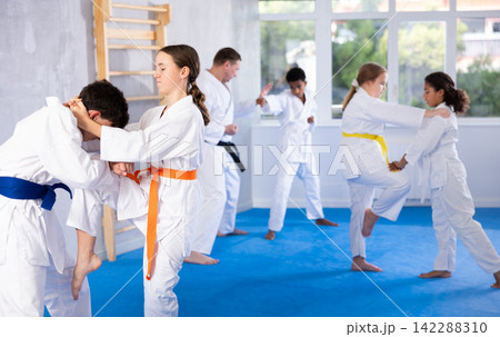 Teenage girl performing knee strike to boy in sparring during jiu-jitsu class Teenage girl performing knee strike to boy in sparring during jiu-jitsu class 142288310