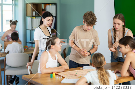 Teenage students playing board game around table Teenage students playing board game around table 142288338