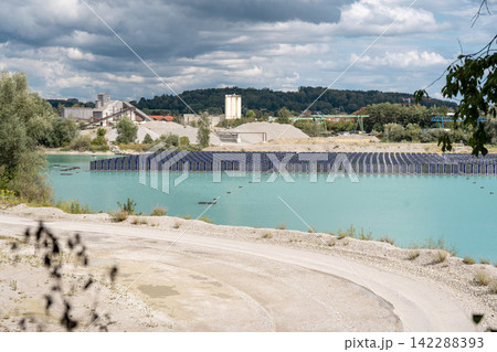 Vertical floating solar panels on the Gilching quarry lake in Bavaria, Germany, beside a gravel and crushing plant, renewable energy infrastructure, industrial landscape and innovative clean 142288393