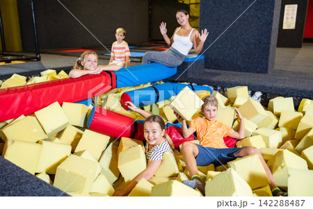 Preteen girl and boy floundering in pit with foam cubes Preteen girl and boy floundering in pit with foam cubes 142288487