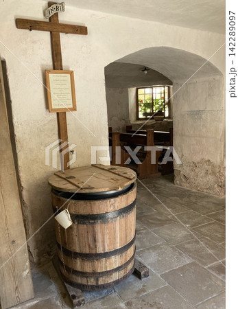 Interior of a small traditional alpine chapel with benches and fresh water tank for travelers to use it free 142289097
