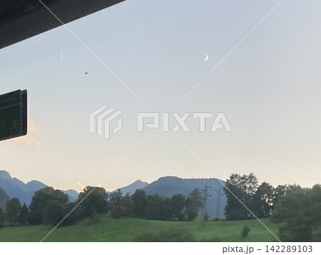 Serene alpine landscape with distant mountain silhouettes under soft twilight sky Serene alpine landscape with distant mountain silhouettes under soft twilight sky 142289103
