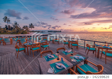 Gorgeous overwater dining deck glowing pastel dusk vivid azure Maldives lagoon terrace resort tables. Luxury honeymoon travel paradise scenic. Exotic couples getaway decor wallpaper Gorgeous overwater dining deck glowing pastel dusk vivid azure Maldives lagoon terrace resort tables. Luxury honeymoon travel paradise scenic. Exotic couples getaway decor wallpaper 142289620