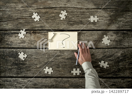 Eight puzzle pieces around question mark and hand Eight puzzle pieces around question mark and hand 142289717