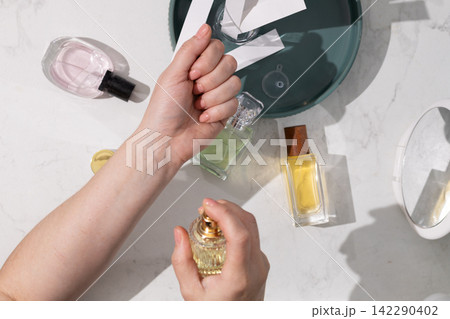 Hand Spraying Perfume on Marble Vanity Amid Luxury Fragrance Collection Hand Spraying Perfume on Marble Vanity Amid Luxury Fragrance Collection 142290402