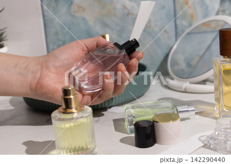 Handheld pink perfume bottle by spray nozzle on marble vanity - premium display Handheld pink perfume bottle by spray nozzle on marble vanity - premium display 142290440
