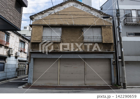 ひび割れたモルタル壁が歴史を物語る、昭和レトロな看板建築の古い店舗 ひび割れたモルタル壁が歴史を物語る、昭和レトロな看板建築の古い店舗 142290659