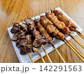 木目調のテーブルの上に並べられた美味しそうな居酒屋メニューの焼き鳥盛り合わせ 木目調のテーブルの上に並べられた美味しそうな居酒屋メニューの焼き鳥盛り合わせ 142291563