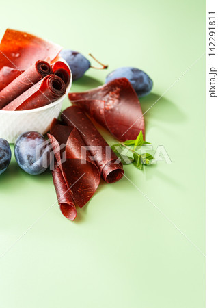 Homemade plum pastila rolls with fruit on soft green background Homemade plum pastila rolls with fruit on soft green background 142291811