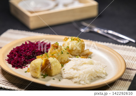 Potato dumplings filled with minced meat, topped with fried onions, served with sauerkraut and red cabbage Potato dumplings filled with minced meat, topped with fried onions, served with sauerkraut and red cabbage 142292610