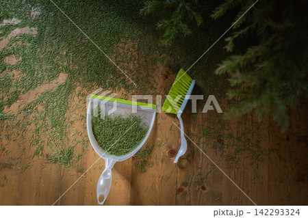 Dustpan collecting fallen needles under Christmas tree Dustpan collecting fallen needles under Christmas tree 142293324