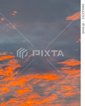 夕日に鮮やかなオレンジ色に染まる雲と暗い空 / ドラマチックな夕焼け空の幻想的な背景素材 夕日に鮮やかなオレンジ色に染まる雲と暗い空 / ドラマチックな夕焼け空の幻想的な背景素材 142293882