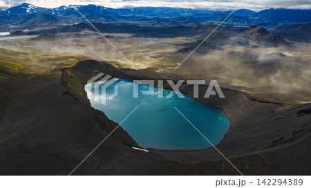 Aerial view of crater lake with turquoise water surrounded by dark volcanic terrain, ytra Iceland 142294389