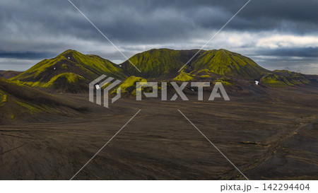 Moss-covered volcanic mountains with dark lava plains, Iceland Moss-covered volcanic mountains with dark lava plains, Iceland 142294404