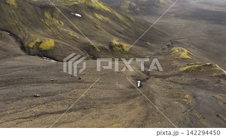 Aerial view of volcanic valley with moss-covered mountains and meltwater stream, Iceland Aerial view of volcanic valley with moss-covered mountains and meltwater stream, Iceland 142294450