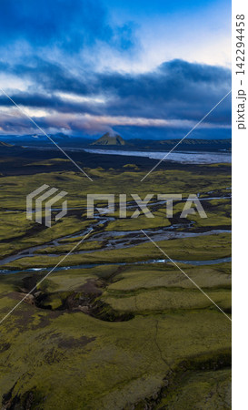 Aerial view of moss-covered lava plains with braided rivers and volcanic cone, Iceland 142294458