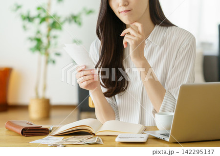 領収書を持って困った顔をするミドルエイジの日本人女性の手元のアップ 領収書を持って困った顔をするミドルエイジの日本人女性の手元のアップ 142295137