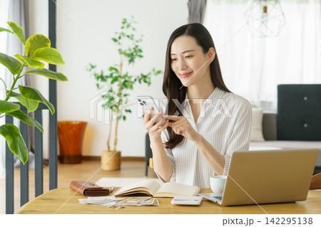 リビングでスマホを操作するミドルエイジの日本人女性 142295138
