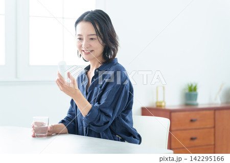 サプリメントを服用する中高年女性 サプリメントを服用する中高年女性 142295166