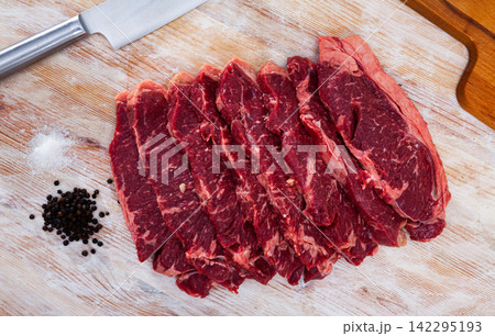 Fresh raw beef meat with pepper spices and knife on light wooden background Fresh raw beef meat with pepper spices and knife on light wooden background 142295193