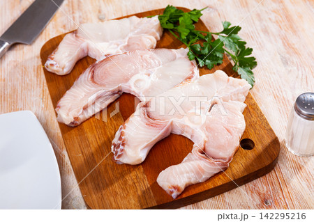 Pieces of fresh blue shark on wooden surface with greens Pieces of fresh blue shark on wooden surface with greens 142295216