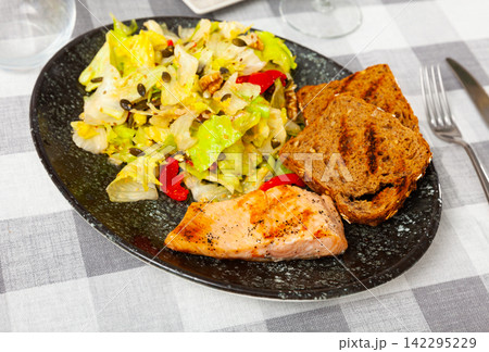 Grilled salmon steak, toasts and fresh lettuce salad Grilled salmon steak, toasts and fresh lettuce salad 142295229