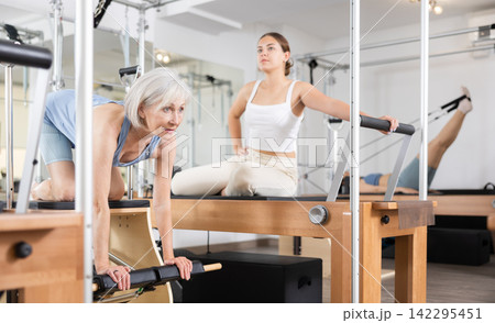 Elderly woman in sportswear training pilates performer bed in gym 142295451