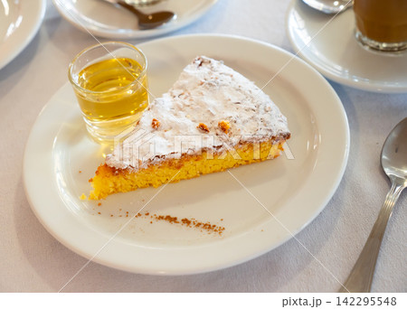 Slice of Tarta de Santiago with coffee with milk and wine Slice of Tarta de Santiago with coffee with milk and wine 142295548
