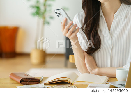 スマホを操作するミドルエイジの女性の手元のアップ スマホを操作するミドルエイジの女性の手元のアップ 142295600