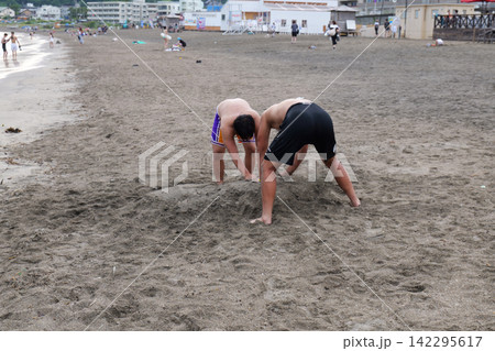 Kamakura Beach in Japan with people enjoying the sea and sandy shore Kamakura Beach in Japan with people enjoying the sea and sandy shore 142295617
