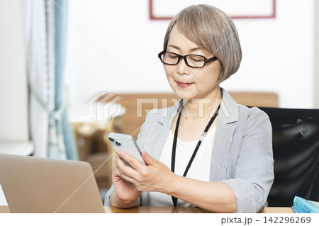 オフィスで仕事をするシニア女性 オフィスで仕事をするシニア女性 142296269