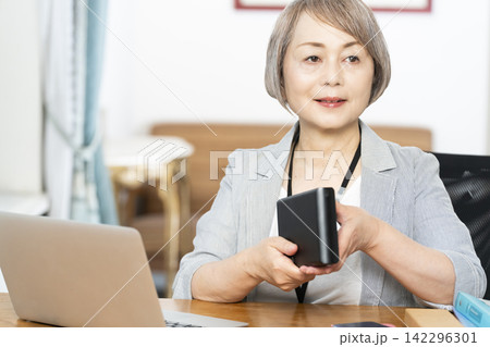 オフィスで仕事をするシニア女性 オフィスで仕事をするシニア女性 142296301