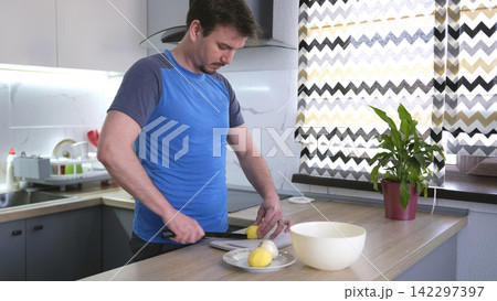 A young chef cuts raw potatoes. The process of cooking fried potatoes. A guy cooks a delicious dinner for his boyfriend A young chef cuts raw potatoes. The process of cooking fried potatoes. A guy cooks a delicious dinner for his boyfriend 142297397