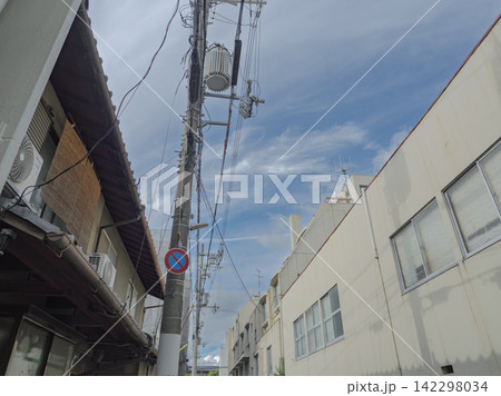 下町の路地で見上げる電柱と複雑に交差する電線と青空 下町の路地で見上げる電柱と複雑に交差する電線と青空 142298034