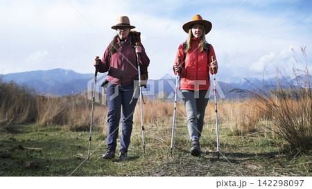 Two best friends are walking through an autumn park in the foothills. Students travel and have fun. Vacations and weekends Two best friends are walking through an autumn park in the foothills. Students travel and have fun. Vacations and weekends 142298097