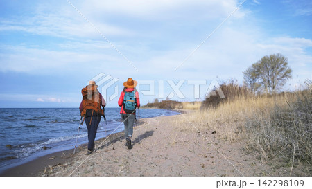 Two close friends are walking along an abandoned beach along the sea, view from the back. Freedom, travel, and a long-awaited vacation 142298109