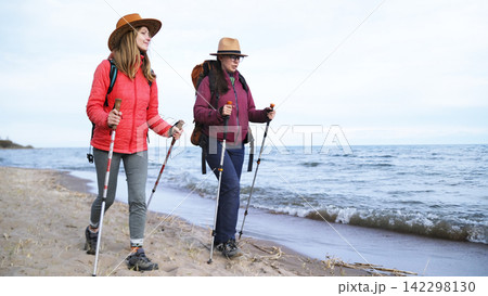 Active sports. Healthy lifestyle. Adventures and travels. Two bright beauties are strolling along the beach. Both have backpacks Active sports. Healthy lifestyle. Adventures and travels. Two bright beauties are strolling along the beach. Both have backpacks 142298130